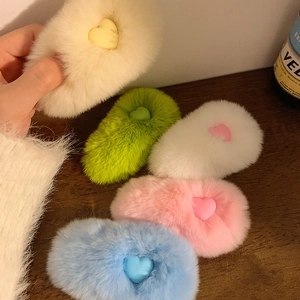 Five colorful plush heart hair clips in beige green pink white and blue on wood