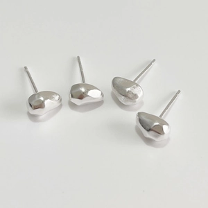 Macro detail of four irregular pebble-shaped 925 sterling silver stud earrings with high polish