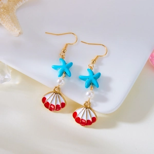Detail of ocean-themed earrings featuring starfish, seashells, and pearls on a white plate