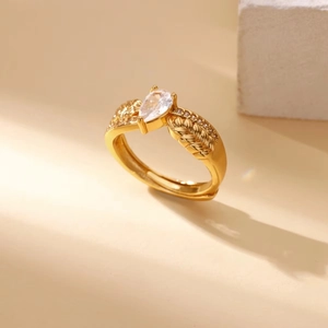 Detail of gold ring featuring pear-cut gemstone and intricate feather pattern engraving