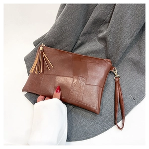 Detail of brown patchwork leather clutch with tassel zipper and wrist strap on suit fabric