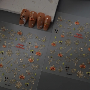 Close-up of Halloween nail stickers with gold foil pumpkins, ghosts, and spider webs