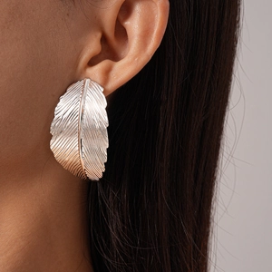 Detailed close-up of large silver leaf earrings with intricate vein textures on model