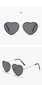 Detail view of heart-shaped sunglasses with dark grey lenses and gold metal frames