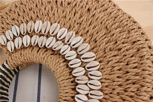 Detail of semicircular paper straw bag with shell decor and black-white striped handles