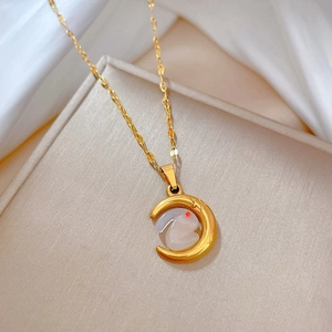 Detail of gold moon and white rabbit pendant on water wave chain over silk background