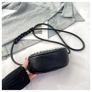 Detail of black pebbled leather crescent bag with rhinestone trim and braided strap
