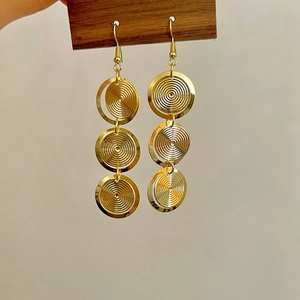 Vue détaillée de boucles d'oreilles dorées à triple cercle et texture spirale