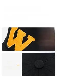 Detail of yellow letter W embroidery with vintage distressed edges on a black cotton cap