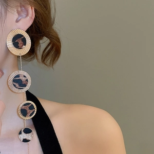 Detailed close-up of long leopard print fringe earrings with gold geometric circles