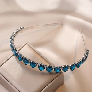 Detailed view of emerald blue heart gemstones on a silver metallic headband over silk