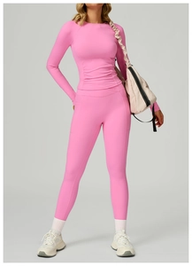 Detail eines Yoga-Sets in leuchtendem Pink mit Langarm-Crop-Top und figurbetonter Sporthose