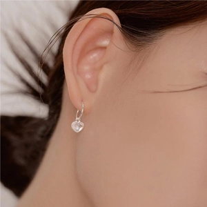 Close-up of minimalist heart dangle earrings with clear cubic zirconia on a female model