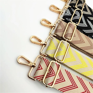 Close-up of wide woven bag straps with chevron patterns and gold metal buckles