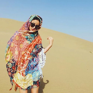 Close-up of bohemian printed shawl with colorful geometric patterns and white tassels