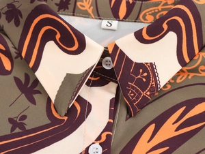 Detail view of collared printed shirt featuring green and orange patterns with size S label