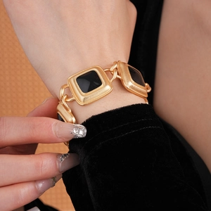Close-up of a vintage gold bracelet with square links and black faceted gemstones