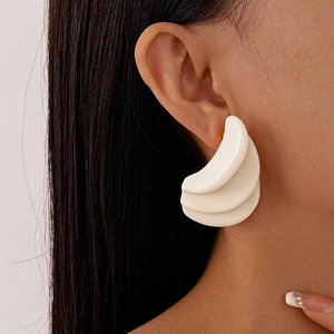 Close-up of three-tier geometric resin earrings in cream white with wavy fan design