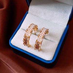 Detail of 18K gold plated C-shaped earrings with pearls and zircons in a jewelry box