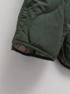 Detail shot of diamond-quilted cuffs on a dark green lightweight padded jacket