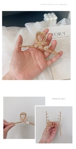 Detail of golden metal flower hair claw clip with pearl pendant and rhinestone center