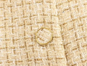 Macro shot of beige tweed fabric with gold metallic thread, sequins and a matching button