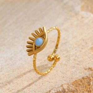Macro shot of gold evil eye open ring with blue stone and diamond textured band