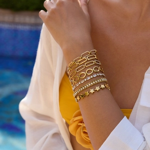 Détail de bracelets superposés en acier inoxydable plaqué or 18K avec étoiles et zircon