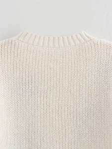 Gros plan du col rond côtelé et de la texture en maille du pull en laine blanc cassé