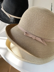 Close-up of woven straw hats in three colors with matching ribbon bow decorations