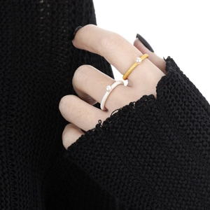Minimalist textured gold and silver rings with pearls worn by a model on white background
