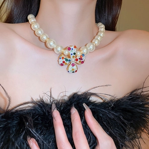 Detailed close-up of model wearing a pearl necklace with a colorful cross pendant