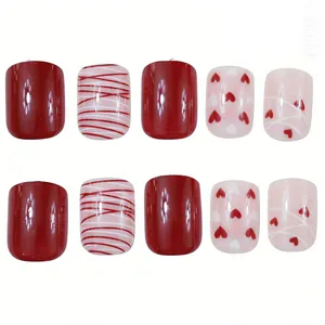 Detail of short square glossy press-on nails with red hearts and stripe designs