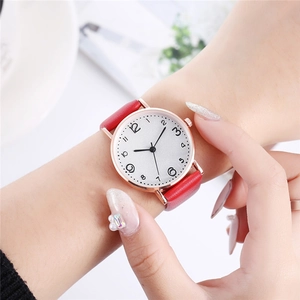 Close-up of elegant gold watch with white dial and red leather strap on a female wrist