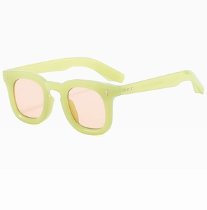 Detail of square sunglasses with light green frames, pink lenses, and metal rivets