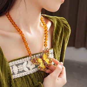 Detail of vintage butterfly necklace with amber beads and crystal pendant on model