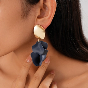 Close-up of deep blue acrylic flower earring with gold stud on model's ear