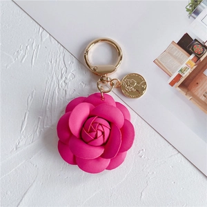 Detail of faux leather camellia flower keychain with gold coin charm and metal ring