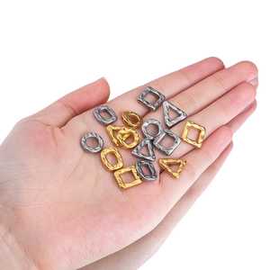 Hammered geometric stainless steel charms in gold and silver held in hand for DIY jewelry