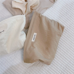 Close-up of pleated cotton makeup bags in cream and coffee with simple wish labels
