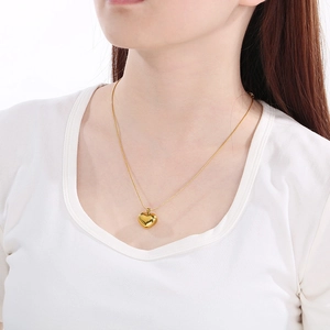 Close-up of a minimalist golden heart pendant necklace worn by a female model