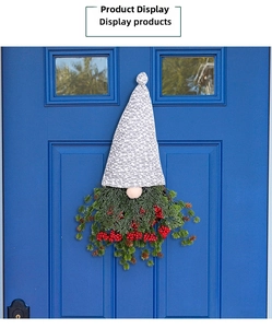 Couronne de Noël gnome avec branches de pin et baies rouges sur une porte bleue