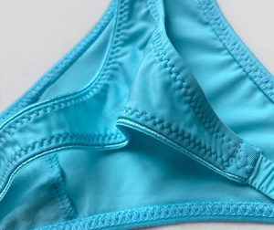 Macro shot of light blue ice silk bikini bottom showing high-elasticity zig-zag stitching