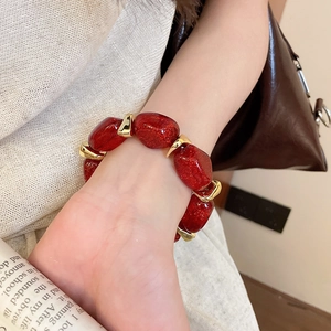 Detailed shot of red glitter acrylic beads and golden metal spacers on a wrist