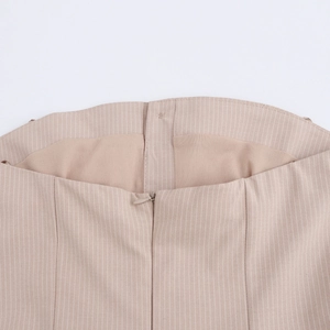 Close-up of invisible zipper and fine striped fabric on a pleated beige skirt