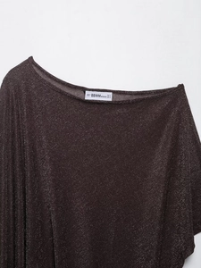 Gros plan sur la texture du tissu violet métallisé et l'étiquette du poncho asymétrique