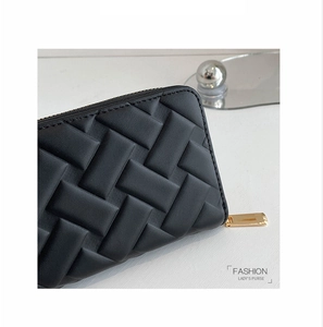 Close-up of black quilted PU leather texture and gold zipper on long women's wallet