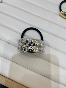 Detail shot of silver irregular hammered metal ring on black elastic hair tie holder