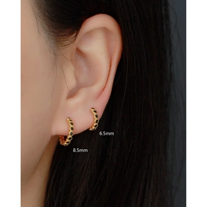 Close-up of gold S925 silver huggie earrings with black stones in 6.5mm and 8.5mm