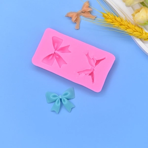 Pink silicone bow mold with finished crafts on blue background for DIY cake baking